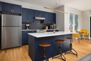 una cocina con armarios azules y una barra con taburetes en Sonder The Frankford, en Filadelfia