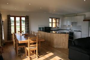 a kitchen and dining room with a wooden table at Berry Barns in Shebbear