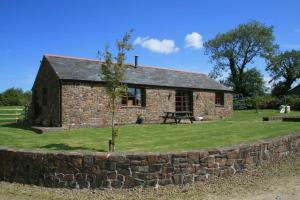 a small stone house with a stone wall at Berry Barns in Shebbear