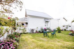 a yard with two chairs and a table in front of a house at Canungra Cottages - Boutique Bed and Breakfast in Canungra