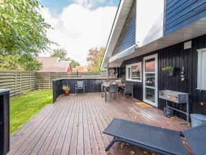 eine Holzterrasse mit einem Tisch und Stühlen auf einem Haus in der Unterkunft 5 person holiday home in Hemmet in Hemmet