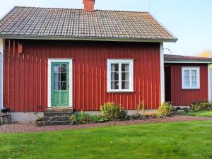 uma casa vermelha com uma porta verde e um quintal em 6 person holiday home in FLOBY em Floby