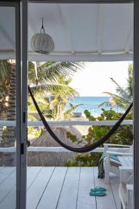 a porch with a hammock and a view of the beach at Coco Tulum Beach Club Hotel in Tulum