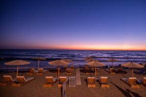 a beach with chairs and umbrellas and the ocean at Romantic Palace Beach Apartments in Agios Gordios