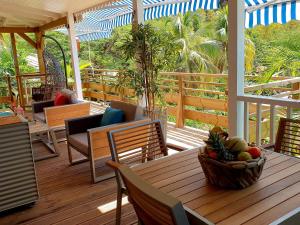 a porch with a table with a basket of fruit on it at LES GÎTES DU DOMAINE DE PETITE-ANSE in Bouillante