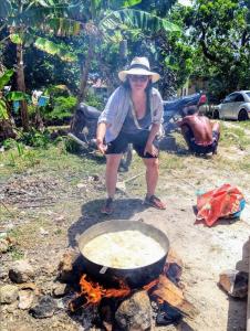 una mujer cocinando comida en una sartén sobre un fuego en POSADA NATIVA DERMA´S INN, en San Andrés