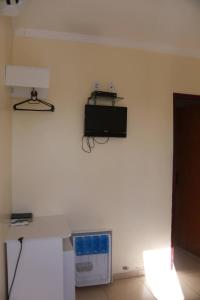 a room with a white wall with a tv on the wall at Pousada D'Lia in Piranhas