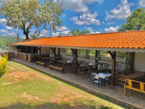 un patio al aire libre con mesas, bancos y techo naranja en Chacara Papagaios en Mairiporã