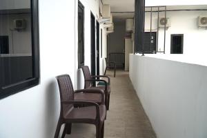 a row of chairs sitting next to a white wall at RedDoorz At Sani Guest House in Balikpapan