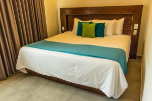 a bedroom with a large bed with blue and green pillows at Aquastar Hotel & Apartments in Mahahual