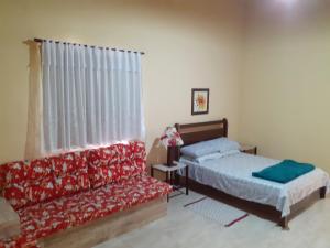 a bedroom with two beds and a couch at Casa Chalé em Penedo in Penedo