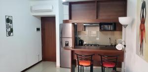 eine Küche mit einer Bar mit Stühlen und einem Kühlschrank in der Unterkunft Departamento Equipetrol Ejecutivo Familiar in Santa Cruz de la Sierra + 13 Fotos