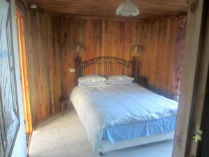 um quarto com uma cama e uma parede de madeira em Catlins Lake Sanctuary em Owaka