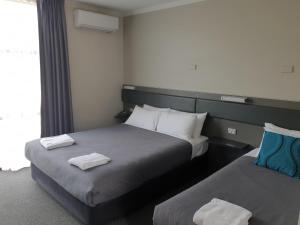 two beds in a hotel room with towels on them at Prospect Hotel Motel in Blacktown