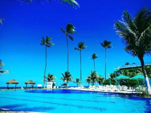 a pool at the beach with palm trees and umbrellas at Ancorar Resort em Porto de Galinhas in Porto De Galinhas
