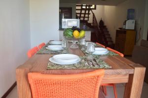 a wooden table with plates and a bowl of fruit at Pipa Arara House - Por Pipa Casas de Praia in Pipa