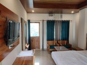 Un dormitorio con una cama, un televisor y una silla. en Hill Hoppers Hotel, en Rishīkesh