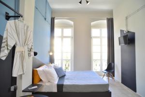 1 dormitorio con 1 cama y 2 ventanas en Habit en Ermoupoli