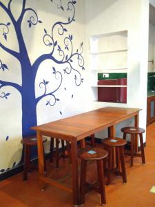 a dining room table with stools and a tree mural at Harmony in Auroville