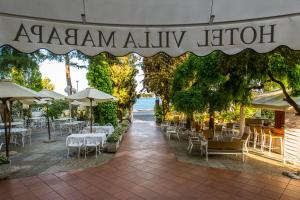 Un restaurante con mesas, sillas y sombrillas. en Hotel Villa Mabapa, en Lido de Venecia