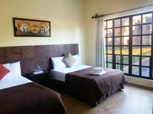 a hotel room with two beds and a window at Hotel Rinconada del Convento in Izamal
