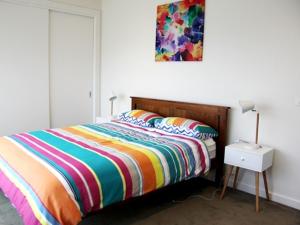 1 dormitorio con 1 cama con un colorido edredón a rayas en Mariner House en Port Fairy