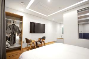 1 dormitorio con TV, mesa y sillas en Gijang Hound Hotel Ilgwang, en Busan