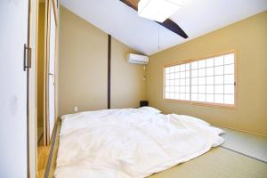 duże białe łóżko w pokoju z oknem w obiekcie Inokuma Kita w mieście Kioto