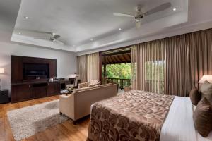 a bedroom with a bed and a couch and a television at Amaya Lake Dambulla in Sigiriya
