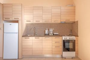 a kitchen with wooden cabinets and a white refrigerator at Akrogiali Studios in Póros Kefalonias