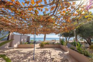a pergola with the beach in the background at Akrogiali Studios in Póros Kefalonias