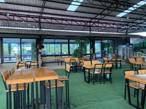 a dining room with tables and chairs and windows at Chadaporn Mae Chaem Hotel in Mae Chaem