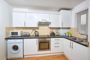 una cucina con armadi bianchi, lavandino e forno a microonde di Shirebrook House Coventry west Midlands a Coventry