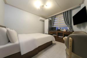 Schlafzimmer mit einem Bett, einem Schreibtisch und einem TV in der Unterkunft Goodstay Grand Motel Chuncheon in Chuncheon