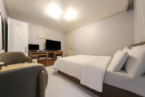 Schlafzimmer mit einem Bett und einem Schreibtisch mit einem TV in der Unterkunft Goodstay Grand Motel Chuncheon in Chuncheon