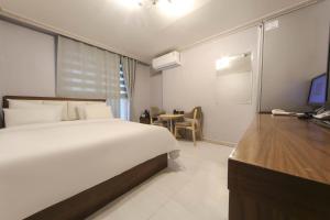 a bedroom with a large bed and a desk with a television at Goodstay Grand Motel Chuncheon in Chuncheon