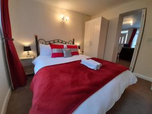 a bedroom with a large bed with red pillows at Lucea Cottage in Craven Arms