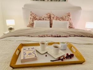 a tray with two cups and a cake on a bed at Apartman Korina in Otočac