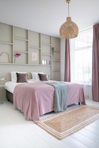 a bedroom with a large bed with a pink blanket at Boutique Hotel - de Stadsherberg Alphen in Alphen aan den Rijn