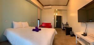 a bedroom with a white bed and a red chair at 墾丁秋莊會館 附限量停車位 不保證有位置 無法事先預留 背包房無車位 預訂後記得加Line聯繫 in Hengchun