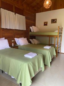 duas camas num quarto com lençóis verdes em Villarejo Pousada e Experiências em Ibiúna