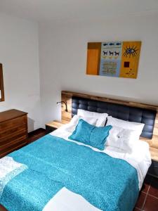 a bedroom with a large bed with a blue blanket at Refugio das Matas in Porto Santo