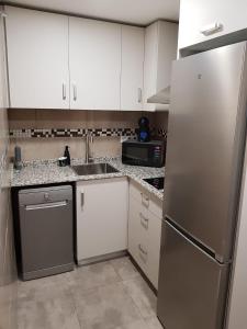 Una cocina con gabinetes blancos y un refrigerador de acero inoxidable. en HR PARADISE RESIDENCIAL LOIX, en Benidorm