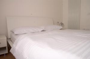 Una cama blanca con sábanas blancas y almohadas. en Windshouse, en Nago-Torbole