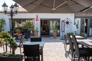 an outdoor patio with tables and chairs and an umbrella at Hôtel Le Peu Breton in Sainte-Marie-de-Ré