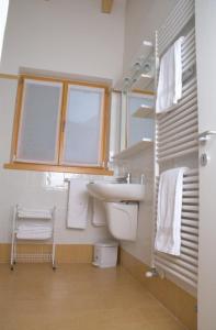 ein Bad mit einem Waschbecken, einem WC und einem Fenster in der Unterkunft Windshouse in Nago-Torbole