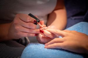 a woman cutting a persons nails with a needle at Hôtel Le Peu Breton in Sainte-Marie-de-Ré