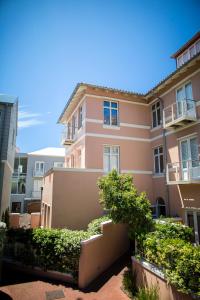 a pink apartment building with bushes in front of it at The Majestic Apartments in Kalk Bay