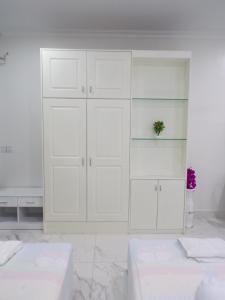 a white room with white cabinets and two beds at Ananta Aster in Phnom Penh