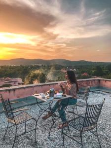 a woman sitting at a table on top of a roof at Tree of Life Resort & Spa Jaipur in Jaipur